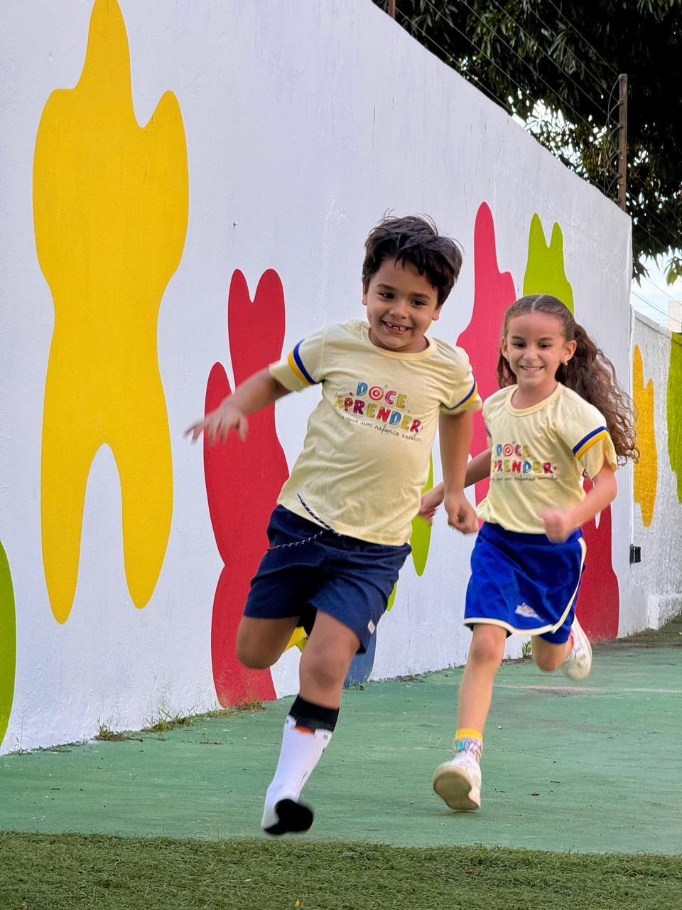 Duas crianças do Doce Aprender correndo e sorrindo, transmitindo alegria